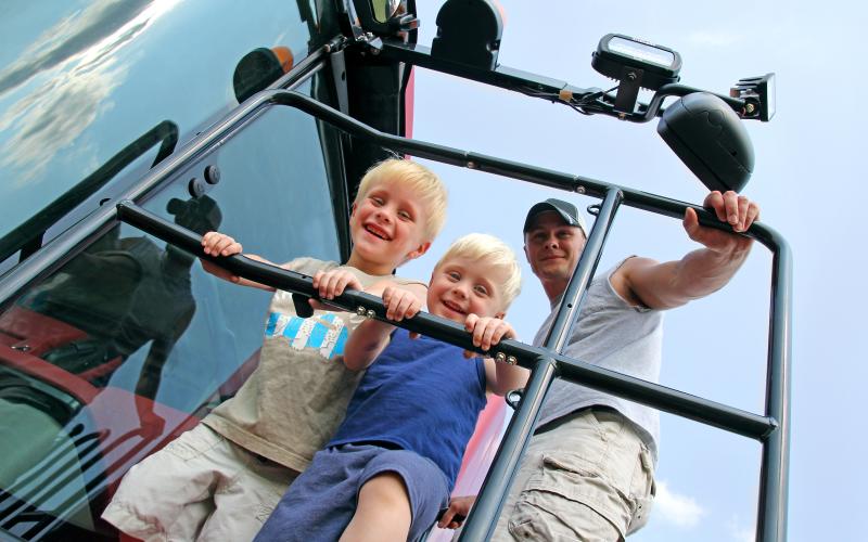 Children and Their Father Smiling as the Climb a Farm Tractor